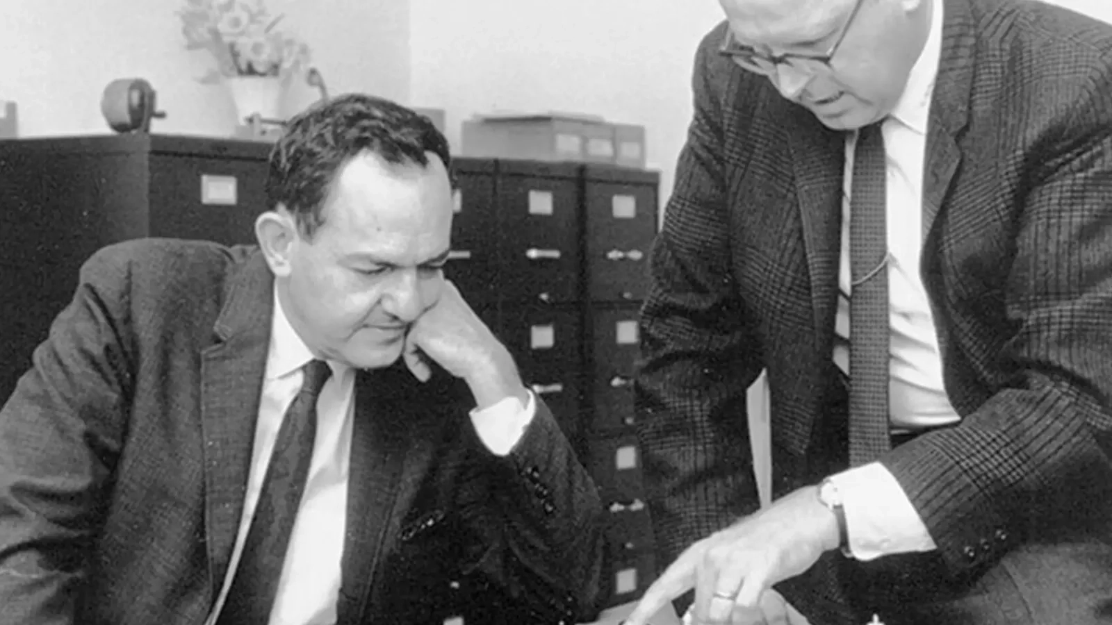 Herbert Simon and Allen Newell in a discussion at a desk
